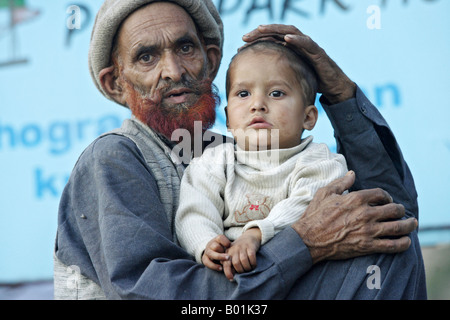 Mann aus dem Erdbebengebiet hält ein Kind, Pakistan Stockfoto