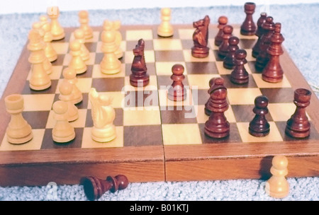 Eine vollständige Sicht auf einem geschnitzten, alles Holz, Schachbrett. Ein Spiel im Gange, die gegenüberliegenden Seiten von hellen und dunklen Stücke decken das Board. Stockfoto