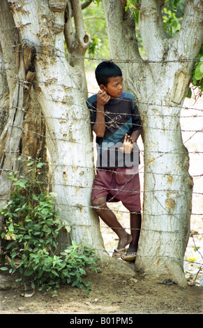 Kambodschanischen Jungen betteln um Geld und Softdrinks hinter Stacheldraht in Choeung Ek Tötungfelder in der Nähe von Phnom Penh Kambodscha Stockfoto