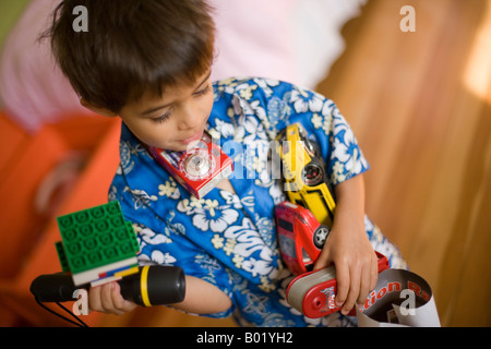 Jungen im Alter von sechs mit Armen und Händen voll tragen eine Auswahl der beliebtesten Spielwaren Stockfoto