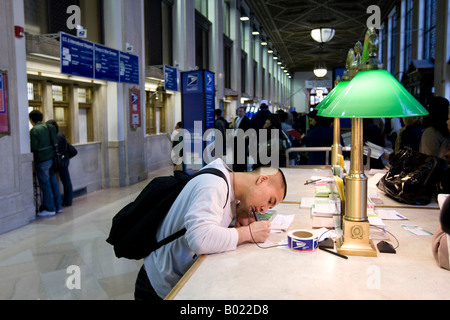 Ein Mann bereitet einen Umschlag zu Post in der Lobby von Farley Post Office in New York 15. April 2008 Stockfoto