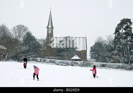 Ide-Hill Village Green im Schnee. mit Kindern spielen und die Marienkirche im Hintergrund Stockfoto