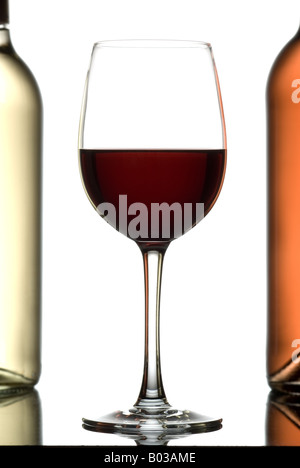 Glas Wein zwischen zwei Flaschen Wein isoliert auf weiss. Stockfoto