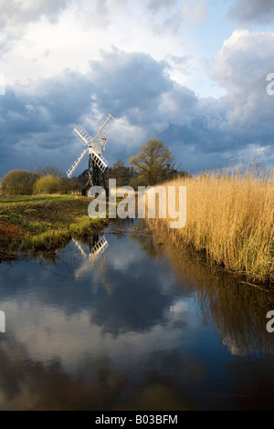 Boardmans Holz öffnen gerahmte Windmühle reflektiert in einem Deich auf den Norfolk Broads mit einem Sturm über Kopf vorbei. Stockfoto