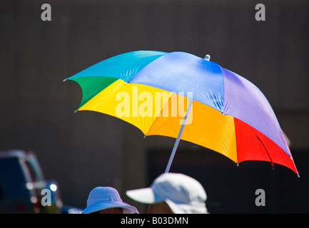 Als Zuschauer bei einer Flugshow in Milwaukee, Wisconsin nutzt einen hellen bunten Regenschirm für Schutz vor der Sonne. Stockfoto