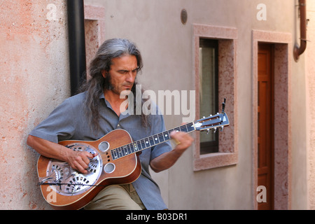 Ein Straßenmusikant Gitarre verliert sich in der Musik, in einer ruhigen Gasse in Malcesine, Italien Stockfoto