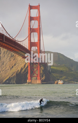 eine Surfer reitet auf eine Welle in der Nähe der Golden Gate Bridge in San Francisco, Kalifornien Stockfoto