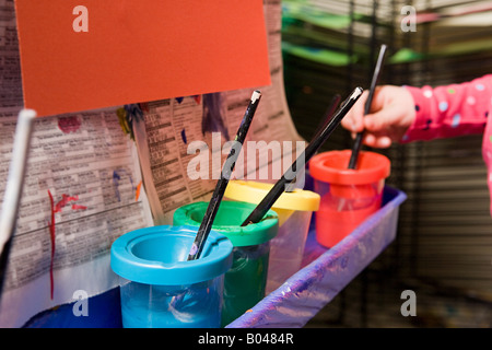 Ein Mädchen, indem einen Pinsel in einen Farbtopf Stockfoto