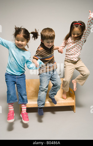 Kinder, die von einer Bank zu springen Stockfoto