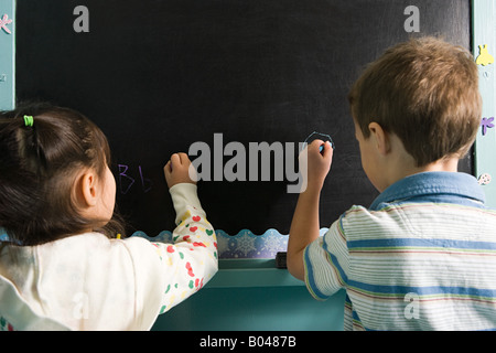 Kinder schreiben auf einer Tafel Stockfoto