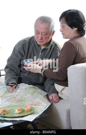 hochrangige asiatische paar nachschlagen Wegbeschreibung mit Karte und GPS-Gerät Stockfoto