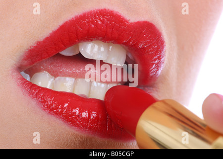 Junge Frau, die Anwendung von rotem Lippenstift Modell veröffentlicht Stockfoto