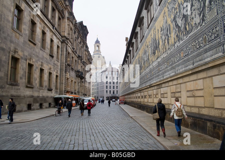 Fürstenzug, der Fürstenzug in Dresden, Deutschland, in der Augustusstraße. Die Leute laufen mit der Frauenkirche auf der Kopfsteinpflasterstraße entlang Stockfoto