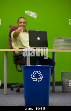 Büroangestellter wirft Plastikflasche in recycling-container Stockfoto