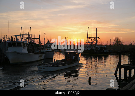 Ein Hummer-Boot geht Angelboote/Fischerboote, die vor Anker liegen auf der Anklagebank bei Belford Meeresfrüchte Coop in Belford New Jersey bei Sonnenaufgang Stockfoto