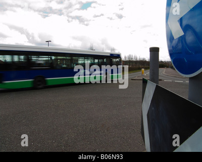 Einen Bus in Richtung Mini-Kreisverkehr mit ein Wegweiser zeigt die Richtung in Swindon Stockfoto