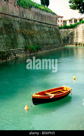 Ein Boot liegt in einem Kanal in Peschiera del Garda am Ufer des Gardasee, Italien Stockfoto
