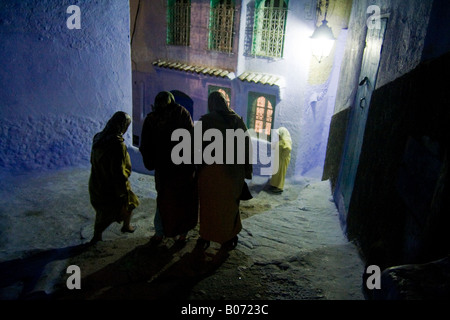 Eine Gruppe von verschleierten Frauen aus Marrakesch gehen Sie die steile und unebene Treppen mit High Heels in einer dunklen Gasse in Tanger, Marokko. Stockfoto