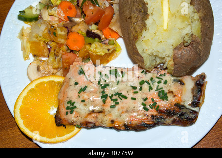 Ein Teller mit gekochten gegrillte ohne Knochen wild Pacific Coho Lachs-Filet mit Gemischter Gemüsesalat und gebutterte Ofenkartoffel. Stockfoto