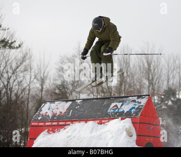 Skifahrer, die über ein kleines Gebäude springen Stockfoto