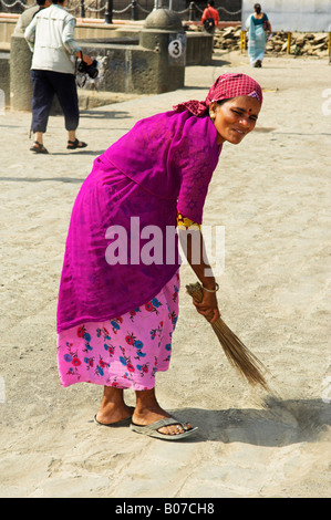 Indische Frau in bunte Kleidung mit Bürste fegt das Gebiet vom Gateway of India Struktur Stockfoto