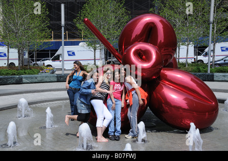 Freunden kuscheln zu Jeff Koons-Skulptur "Balloon Flower (rot)" auf dem Platz vor 7 World Trade Center in Manhattan. Stockfoto