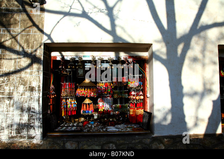 Souvenir Stall und Baum Schatten in einer Gasse in der Altstadt von Lijiang. Stockfoto