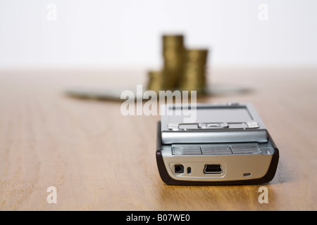 Handy mit gestapelten Münzen im Hintergrund Stockfoto