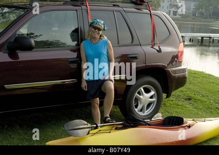 Frau mit Kajak neben GMC Envoy am See Stockfoto