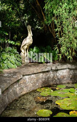 EINE SKULPTUR REIHER SITZT NEBEN EINEM GARTEN-TEICH-UK Stockfoto