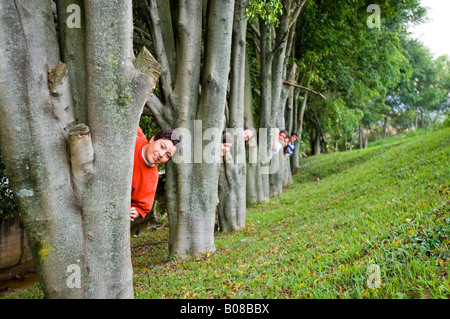 Kinder, die hinter Bäumen Ausschau Stockfoto