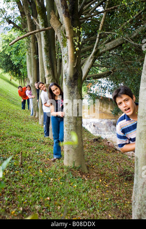 Kinder, die hinter Bäumen Ausschau Stockfoto