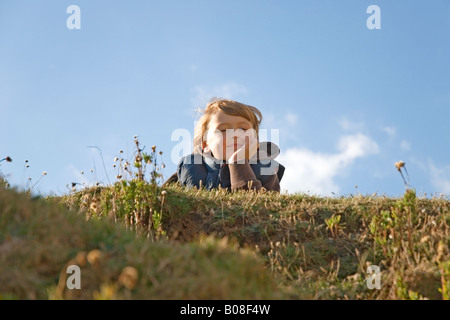 Ein fröhlicher 8-jähriger Junge Festlegung auf dem Rasen und auf der Suche nach selbstgefällig und zufrieden mit sich selbst. Stockfoto