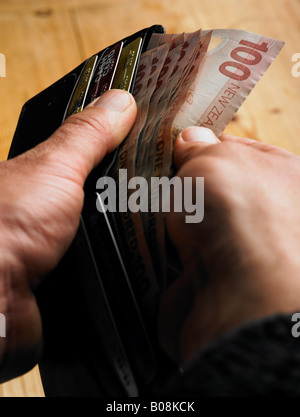 Person durchblättern Nz hundert-Dollar-Noten und Kreditkarte in Brieftasche Stockfoto