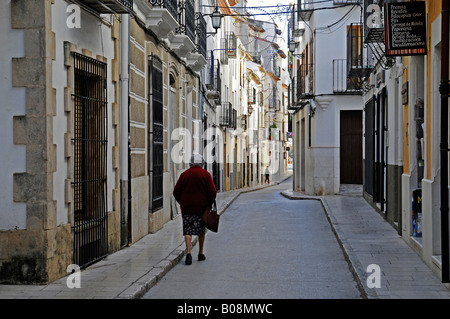 Alte Frau hinunter eine schmale Gasse in der Altstadt von Benissa, Alicante, Costa Blanca, Spanien Stockfoto