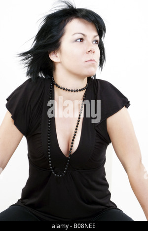 süße schwarzhaarige Frau in einem schwarzen Top mit schwarze Halskette Stockfoto