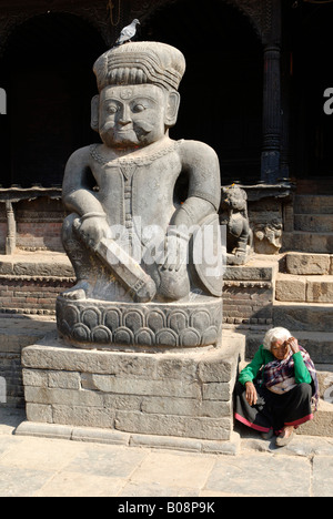 Alte Frau setzte eine große steinerne Statue von Malla Wrestler vor Dattatreya Tempel, Tachupal Tole, Bhaktapur, UNESCO-Wo Stockfoto