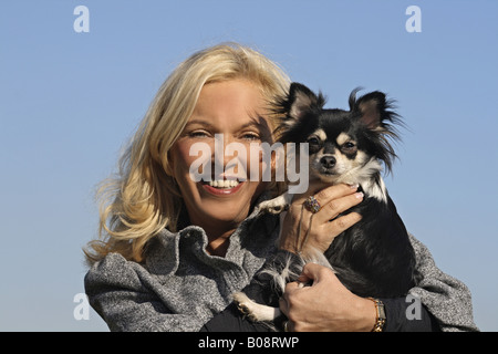 Chihuahua (Canis Lupus F. Familiaris), blonde Frau mit einem langhaarigen Chihuahua auf dem Arm Stockfoto