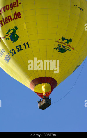 Aufsteigender gelb Heißluft-Ballon mit Brennerflamme auf blauem Himmel, Bad Wiessee, Upper Bavaria, Bavaria, Germany Stockfoto