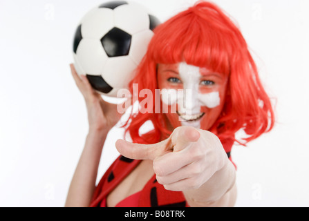 Frau als Schweiz-Fan mit einem Fußball in der Hand, zeigt auf die Kamera Stockfoto