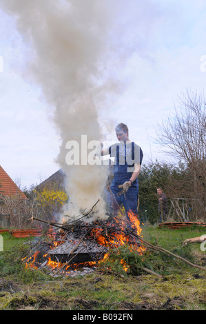 Teenager brennende Gartenabfälle in einem Hof zwar Nachbarn auf, sieht die Mühe Stockfoto