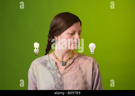 ein Umweltschützer schaut verächtlich auf eine weißglühende Glühlampe Stockfoto