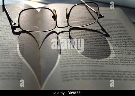 Herzförmigen Schatten der Brille liegen an einem Buch Stockfoto