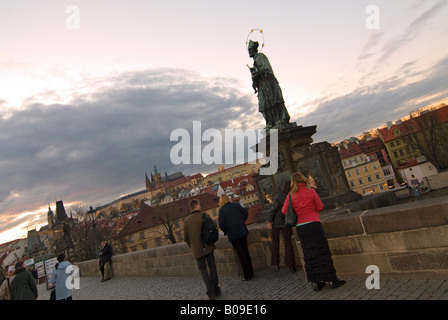 Horizontalen Weitwinkel von St. Johannes von Nepomuk-Statue auf der Karlsbrücke von Touristen bei Sonnenuntergang als Glücksbringer berührt. Stockfoto