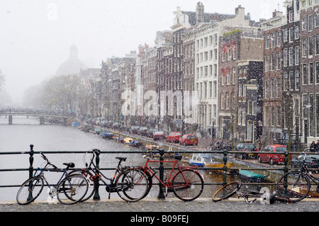 Amsterdam, Ansicht nordöstlich canal entlang Singel in fallenden Schnee von Torensteeg Brücke, Fahrräder Stockfoto