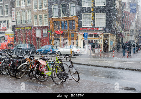 Amsterdam, Nieuwezijds Voorburgwal Straße in fallenden Schnee, Fahrräder, bars Stockfoto