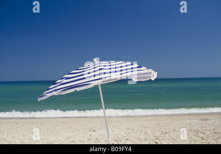 Blau-weiß gestreiften Sonnenschirm gesehen gegen Meer und tiefblauen Himmel auf sandigen Barril Strand ILHA DE TAVIRA ALGARVE PORTUGAL Stockfoto
