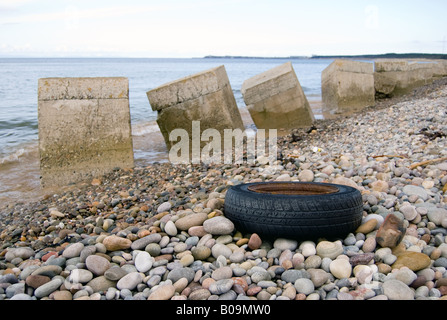 Ein Reifen und konkrete Hindernisse auf Roseisle Strand Stockfoto