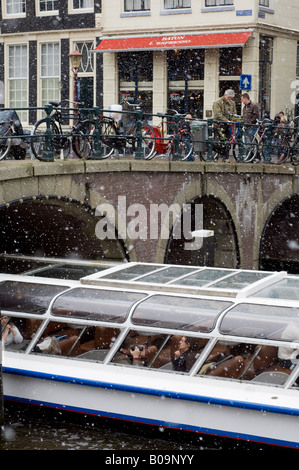 Amsterdam, Touristenboot Weitergabe Herengracht Kanal, in fallenden Schnee unter Brücke Stockfoto