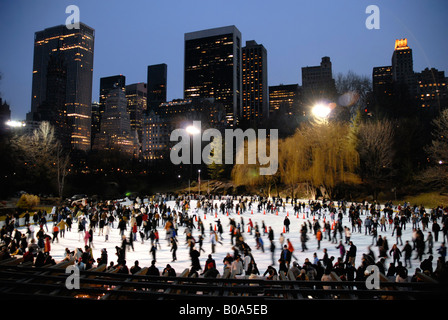 Eislaufen im Central Park bei Nacht im Winter Manhattan Skyline im Hintergrund New York USA Stockfoto